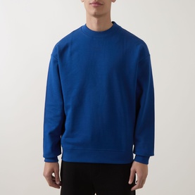 Model wearing Hugo crew neck sweatshirt in Open Blue, relaxed fit, 100% cotton, styled with black trousers