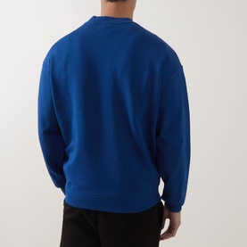 Model wearing Hugo Open Blue cotton crew neck sweatshirt, back view, styled with black trousers
