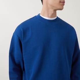 Model wearing Hugo Open Blue cotton crew neck sweatshirt with tonal logo lettering, styled with white crew neck underneath