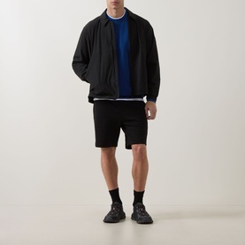 Model wearing Hugo Open Blue cotton crew neck sweatshirt with black bomber jacket, black shorts and black trainers