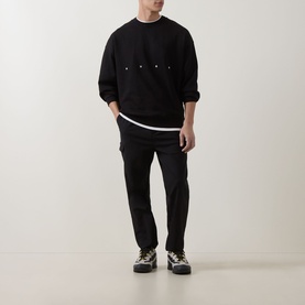 Model wearing Hugo black cotton crew neck sweatshirt with snap details, styled with black trousers and chunky trainers.