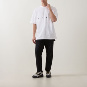 Model wearing Hugo Crew Neck T in Natural white with small logo detail, styled with black trousers and chunky trainers.