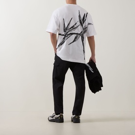 Model wearing Hugo Crew Neck T in natural white with abstract botanical back print, styled with black cargo trousers and jacket.