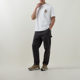 Model wearing Hugo Detzi Logo T-Shirt in Natural with chest graphic logo, styled with dark cargo trousers and trail trainers