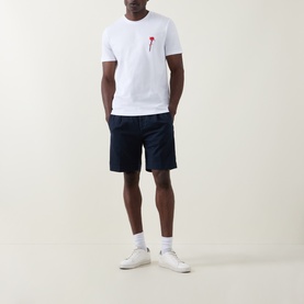 Model wearing Hugo Diflow Logo T-Shirt in white with red chest logo, styled with navy shorts and white trainers.