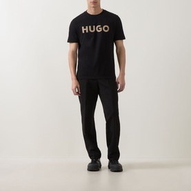 Model wearing Hugo black crew neck T-shirt with large contrast logo print, styled with black trousers and dark trainers.