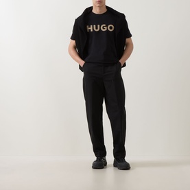 Model wearing Hugo black crew neck T-shirt with logo print, styled with black tailored trousers and black trainers.