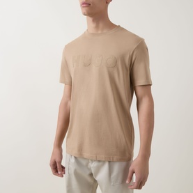 Model wearing Hugo crew neck T-shirt in medium beige, featuring tonal logo lettering, paired with light grey shorts.
