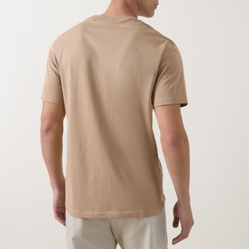 Model wearing Hugo medium beige cotton crew neck T-shirt, rear view, styled with light grey trousers.