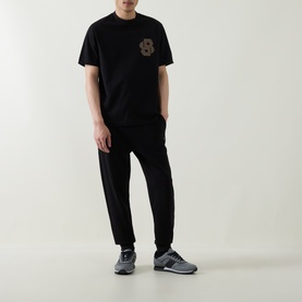 Model wearing Hugo black cotton crew neck sweatshirt with chest graphic, styled with black joggers and grey trainers.