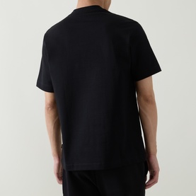 Model wearing Hugo Crew Neck T-shirt in black, rear view, relaxed fit, 100% cotton, styled with black trousers
