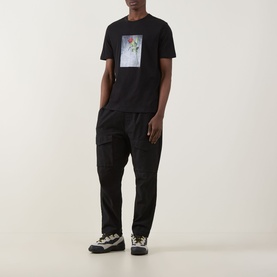Model wearing Hugo Durose Graphic T-Shirt in black with floral photo print, styled with black cargo trousers and multi-coloured trainers.