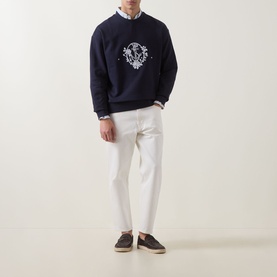 Model wearing Hugo dark blue cotton crew neck sweatshirt with white chest emblem, styled with white trousers and a shirt