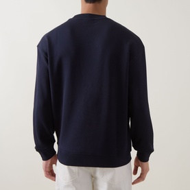 Model wearing Hugo dark blue cotton crew neck sweatshirt, back view, styled with white trousers