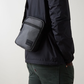 Model carrying Hugo Ethon 2.0 Crossbody Bag in black, textured finish with silver-tone hardware and logo badge, worn over dark jacket.