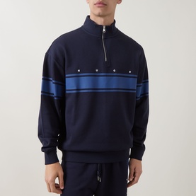 Model wearing Hugo dark blue cotton half-zip sweatshirt with blue chest stripe and stud detailing, styled with matching navy joggers