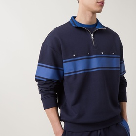 Model wearing Hugo dark blue cotton half-zip sweat with blue chest stripe detail and snap button trim, styled with matching navy joggers
