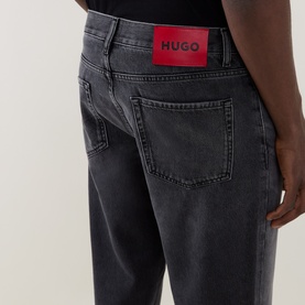 Model wearing Hugo 3049 Jeans in silver grey denim, rear view showing red logo patch on waistband, relaxed fit, 100% cotton