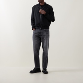 Model wearing Hugo 3049 Jeans in silver grey, styled with a black bomber jacket and black loafers