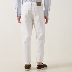 Model wearing Hugo 3049 Jeans in Natural white, straight leg, tan leather patch detail, paired with navy shirt and dark loafers, rear view