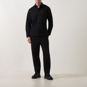 Model wearing Hugo Egrin Logo Overshirt in black with pointed collar, styled with black trousers and chunky black shoes.