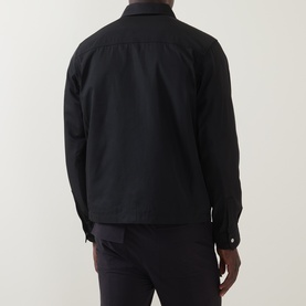 Model wearing Hugo black polyester overshirt, rear view, with dark trousers. Button-front, long sleeves with button cuffs.