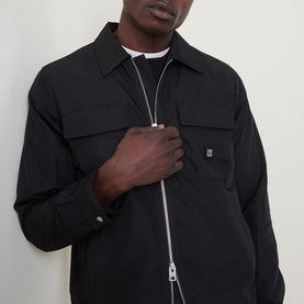 Model wearing Hugo black polyester overshirt with zip fastening, chest pocket, and logo badge, styled over white crew-neck tee