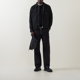 Model wearing Hugo black polyester overshirt with zip fastening, styled with black trousers and carrying a dark bag