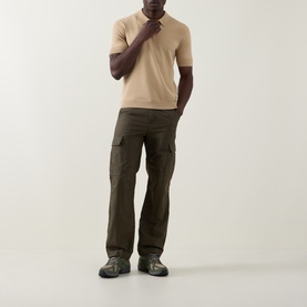 Model wearing Hugo San Peter-CV Knitted Polo Shirt in Medium Beige with dark olive cargo trousers and grey hiking shoes.