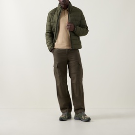 Model wearing Hugo San Peter-CV Knitted Polo Shirt in Medium Beige, styled with olive quilted jacket, dark cargo trousers and grey trainers.