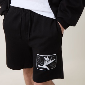 Model wearing Hugo black cotton shorts with botanical graphic print patch detail on left leg, paired with white tee
