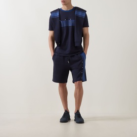 Model wearing Hugo dark blue cotton shorts with side snap detail, styled with matching navy graphic tee and navy trainers