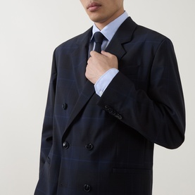Model wearing Hugo dark blue wool suit jacket, double-breasted with black buttons, styled with light blue shirt and navy tie