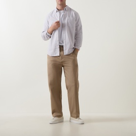 Model wearing Hugo Craysohne263 Straight Leg Trousers in beige, styled with a light blue striped shirt and white trainers.