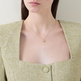 Model with Kate Spade Spade Flower Pav&eacute; Mini Pendant Necklace, gold-tone chain with pav&eacute; cubic zirconia flower pendant, styled with sage green jacket.