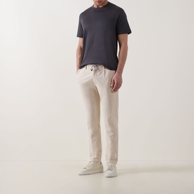 Model wearing Eleventy Girocollo Solid T-Shirt in Black, crew neck, short sleeves, styled with cream drawstring trousers and white trainers.