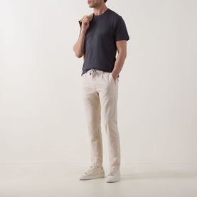 Model wearing Eleventy Girocollo Solid T-Shirt in Black, crew neck, short sleeves, styled with cream trousers and white trainers.