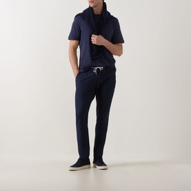 Model wearing Eleventy navy modal-cotton T-shirt with draped scarf detail, styled with matching navy drawstring trousers and suede trainers.