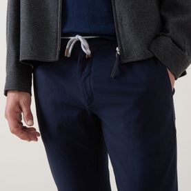 Model wearing Eleventy navy trousers with drawstring waist, styled with a grey zip-up jacket and blue top.