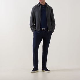 Model wearing Eleventy navy trousers with white drawstring waist, styled with grey jacket, navy polo and cream trainers.