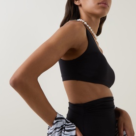 Model wearing Max Mara black bikini top with pearl strap detail, styled with zebra-print skirt