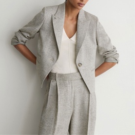 Model wearing Reiss beige tailored blazer and wide-leg trousers, styled with a white V-neck top