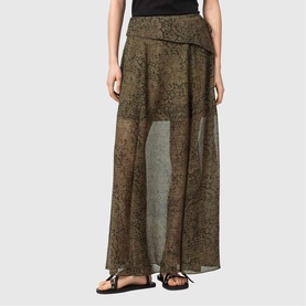 Model wearing All Saints Sali Printed Flared Skirt in Sirius Gold, maxi length with fold-over waist and sheer printed fabric, styled with black