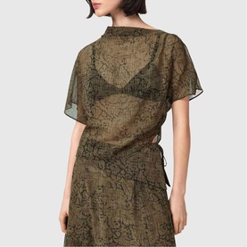Model wearing All Saints Sali Printed Transparent Top in Sirius Gold, shown from back with fixed pleated side seam and sheer overlay.