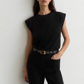 Model wearing Reiss black sleeveless top with shoulder pads, styled with black jeans and a black leather belt with gold buckle