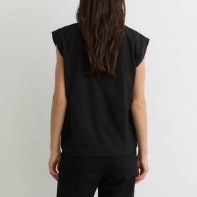 Model wearing Reiss black sleeveless top, rear view, styled with matching black trousers.