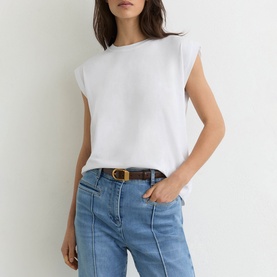 Model wearing Reiss white sleeveless T-shirt with shoulder padding, styled with light blue jeans and a brown belt.