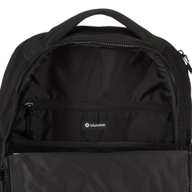 Lululemon New Crew Backpack 22L in Black/Graphite Grey, open top view showing spacious interior compartment with zip pockets and logo lining.