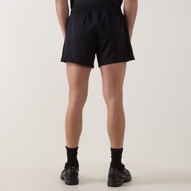 Model wearing Lululemon black performance shorts, rear view, styled with black socks and trainers
