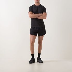 Model wearing Lululemon black performance shorts with matching black T-shirt, socks, and trainers, arms crossed.